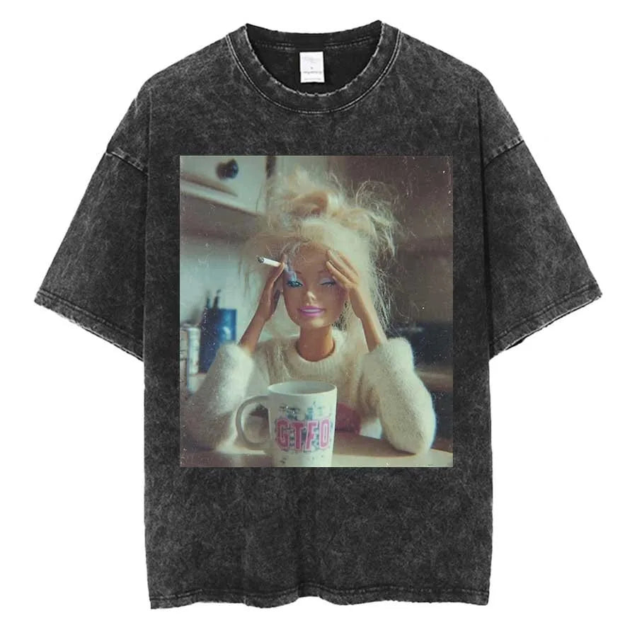 Washed charcoal tee printed with a photograph of a blonde fashion doll sat at a kitchen table holding her head, a lit cigarette in one hand and a mug in front of her