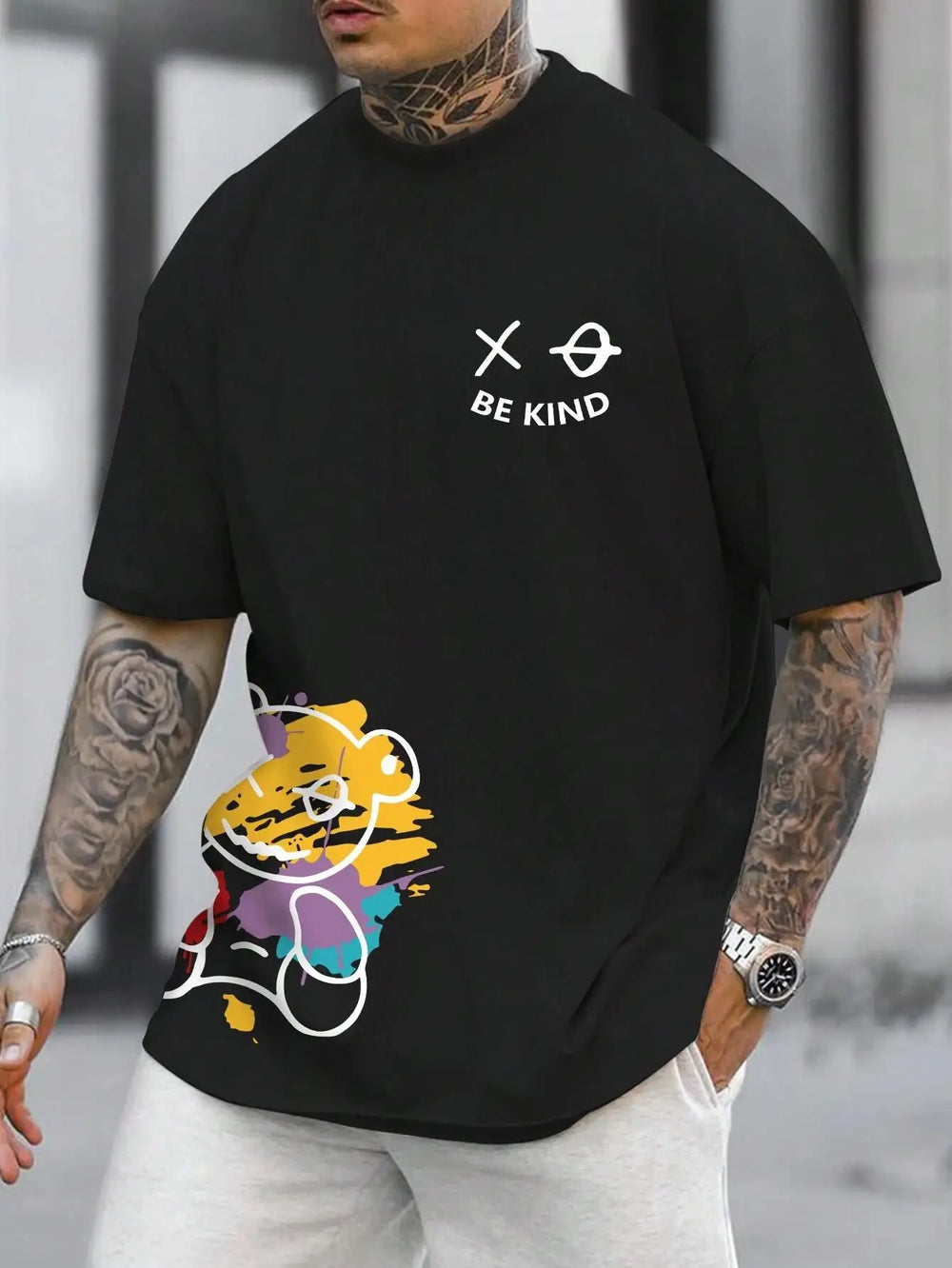 Black cotton tee printed with a graffiti bear and the words BE KIND