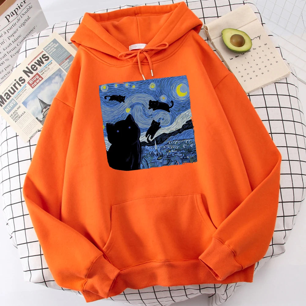 Orange fleece pullover hoodie with a large front print of a swirling starry night sky, a crescent moon and black cats over a village