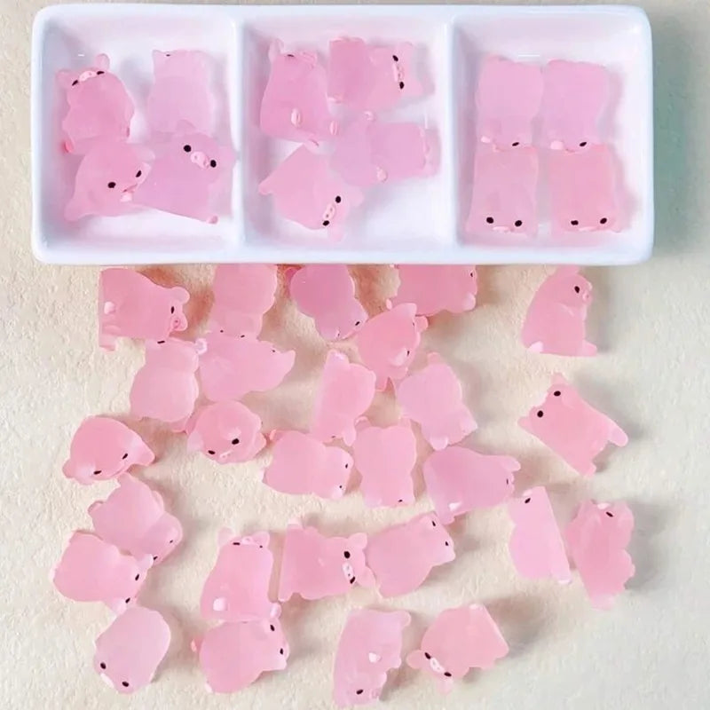 Mini pink resin pigs in a divided tray and scattered on a surface