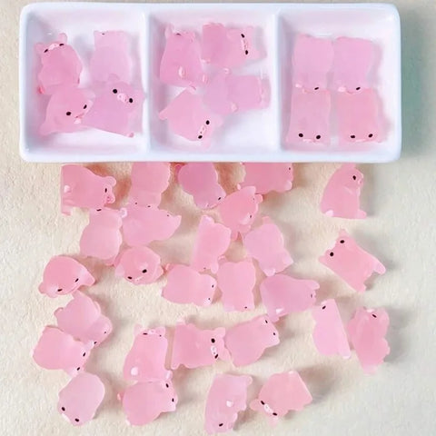 Mini pink resin pigs in a divided tray and scattered on a surface