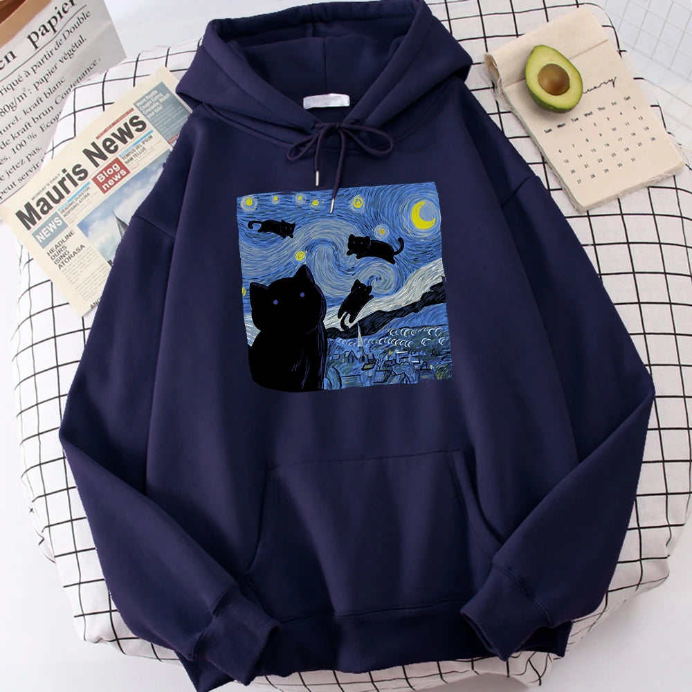 Dark blue fleece pullover hoodie with a large front print of a swirling starry night sky, a crescent moon and black cats over a village