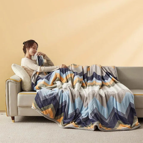 Chevron Stripe: the blanket spread over a sofa in navy, pale blue, grey and orange zigzag bands
