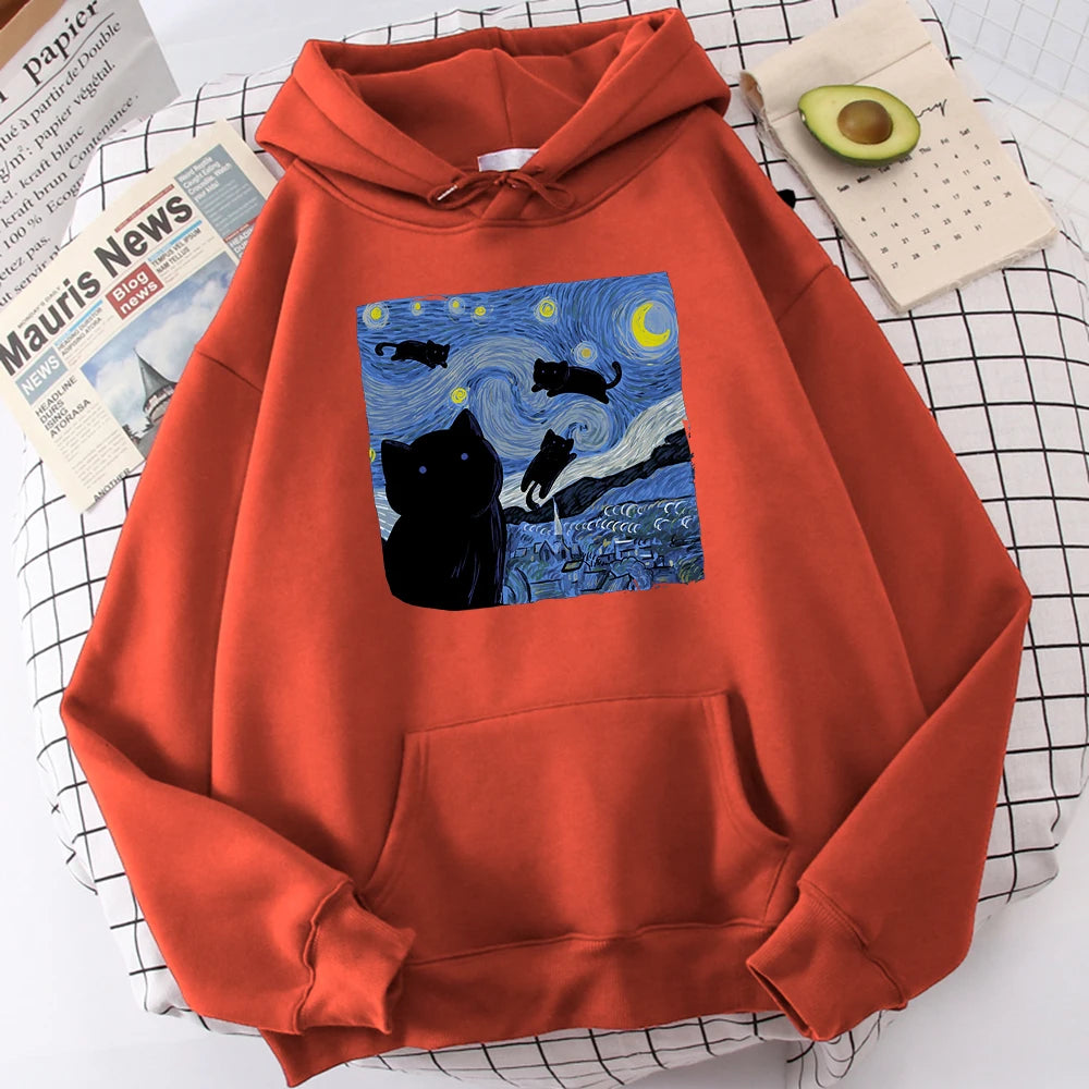 Brick red fleece pullover hoodie with a large front print of a swirling starry night sky, a crescent moon and black cats over a village