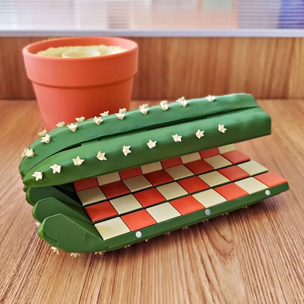 The board part-folded, closing into a green spined cactus shape over the checkered squares