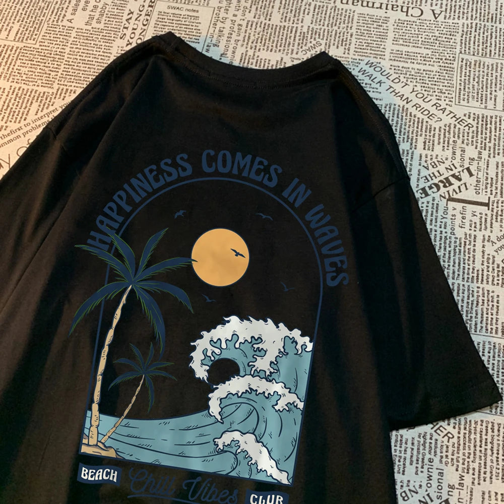 Black cotton tee with a large back print of a breaking wave, palm trees and a low sun, under the arched words Happiness Comes In Waves