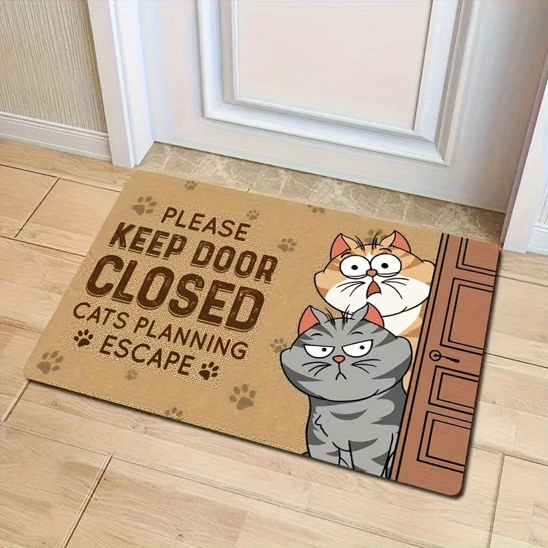 Burlap look doormat with a ginger cat and a grey tabby peering around an open door, in front of a white panelled door