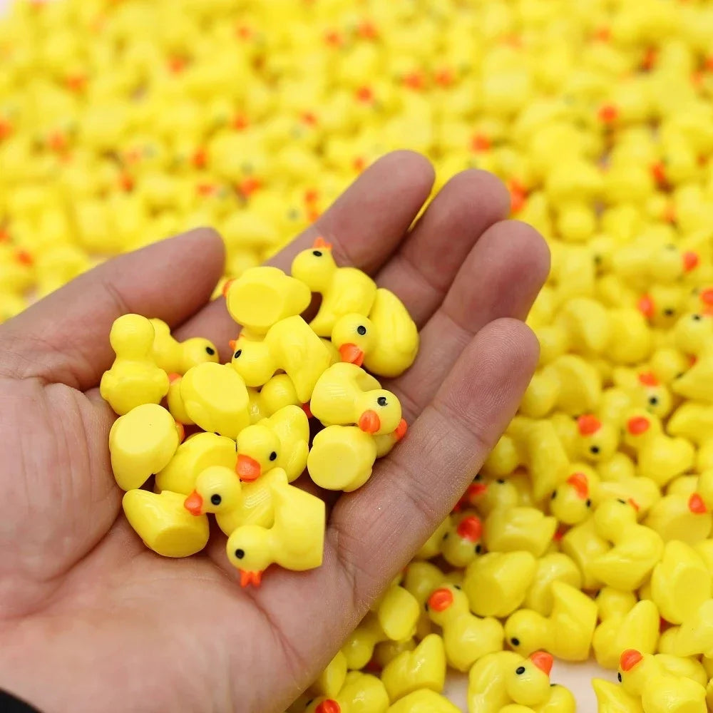 A handful of the tiny yellow ducks held in an adult hand, for scale