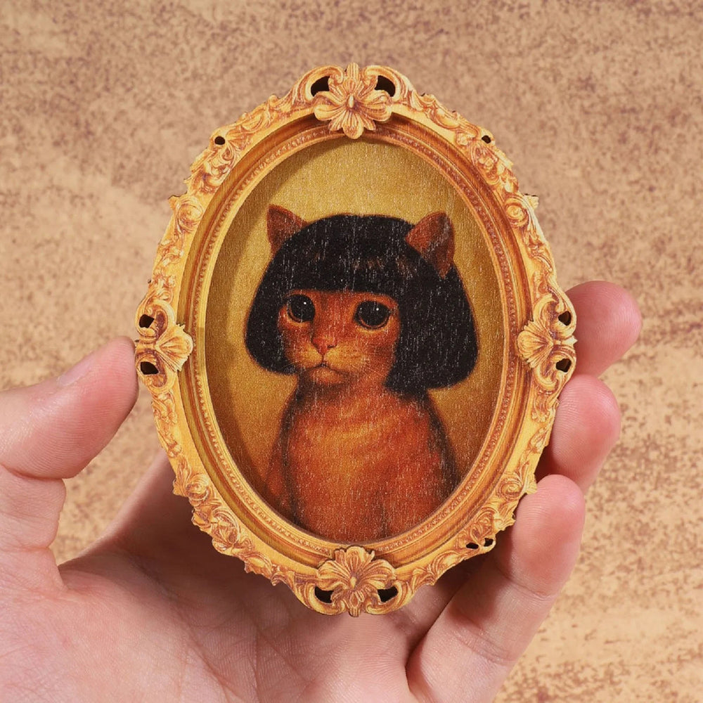 The cat framed magnet held in a hand to show its size