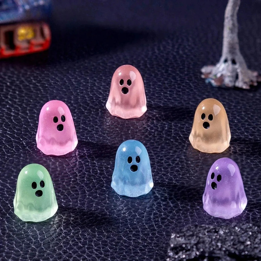 Six of the ghosts scattered on a dark textured surface - the miniature scenery behind them is not included
