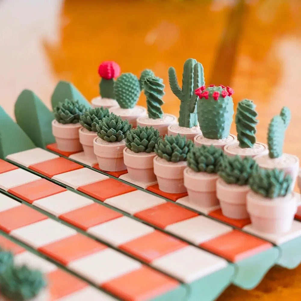 Close-up of the pieces in a paler colourway, blue-green cacti in white pots on coral and white squares