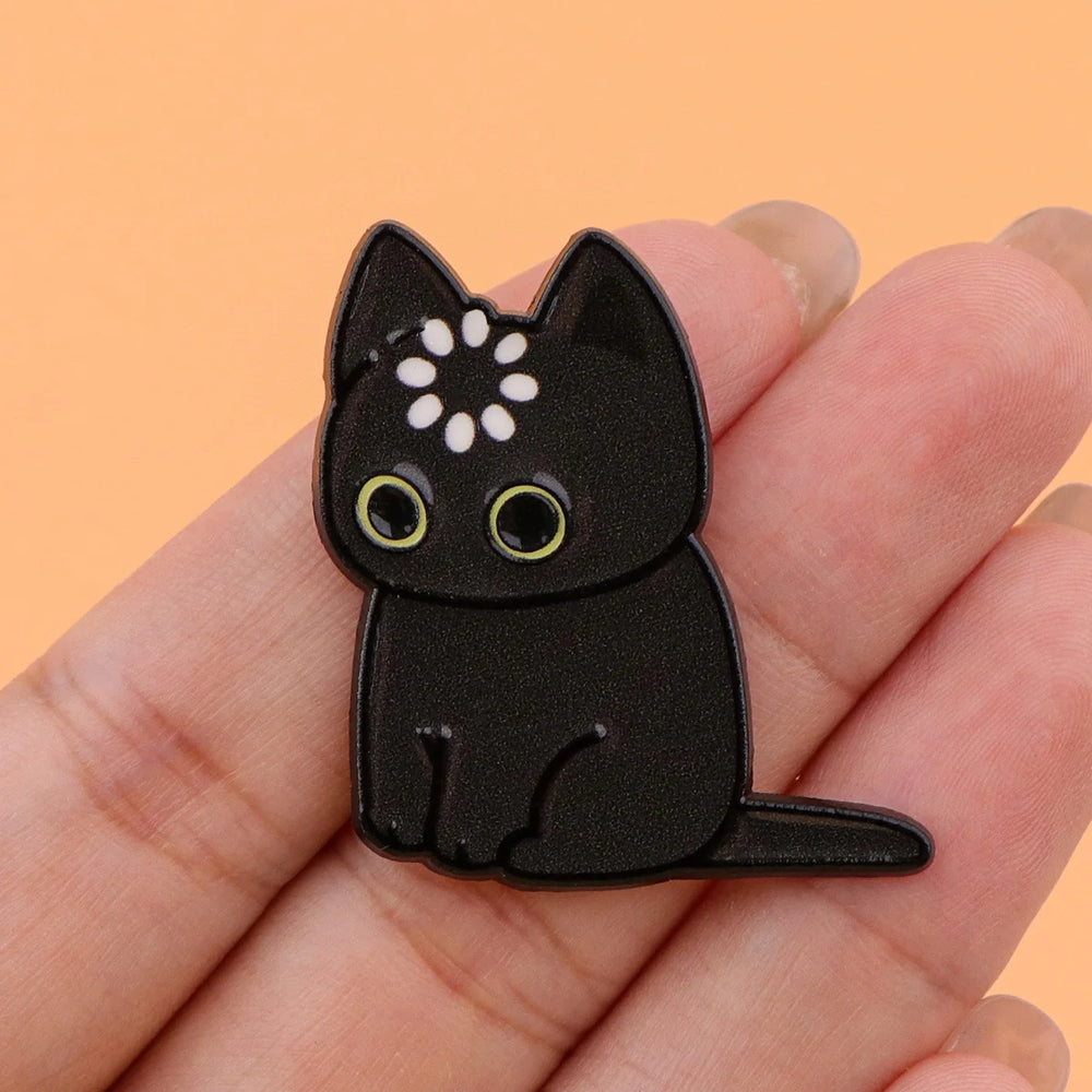 Black cat magnet held in a hand to show its size