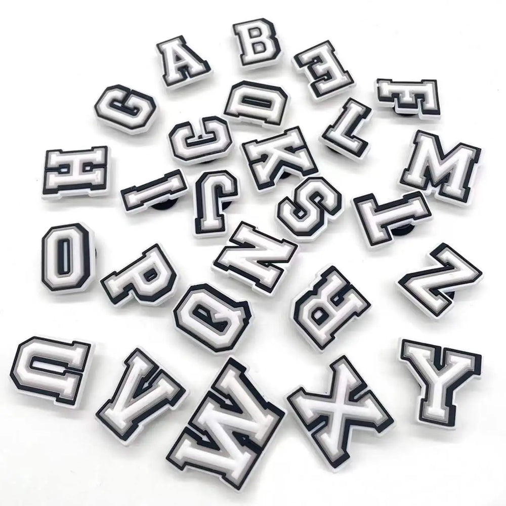 White alphabet letter shoe charms in a pile