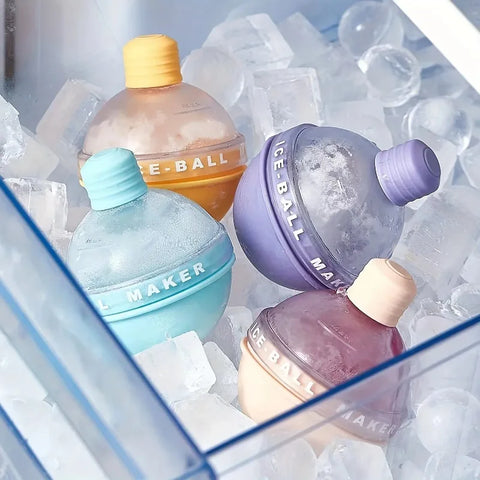 Four round ice ball molds in yellow, blue, purple and peach sitting in a freezer drawer full of ice