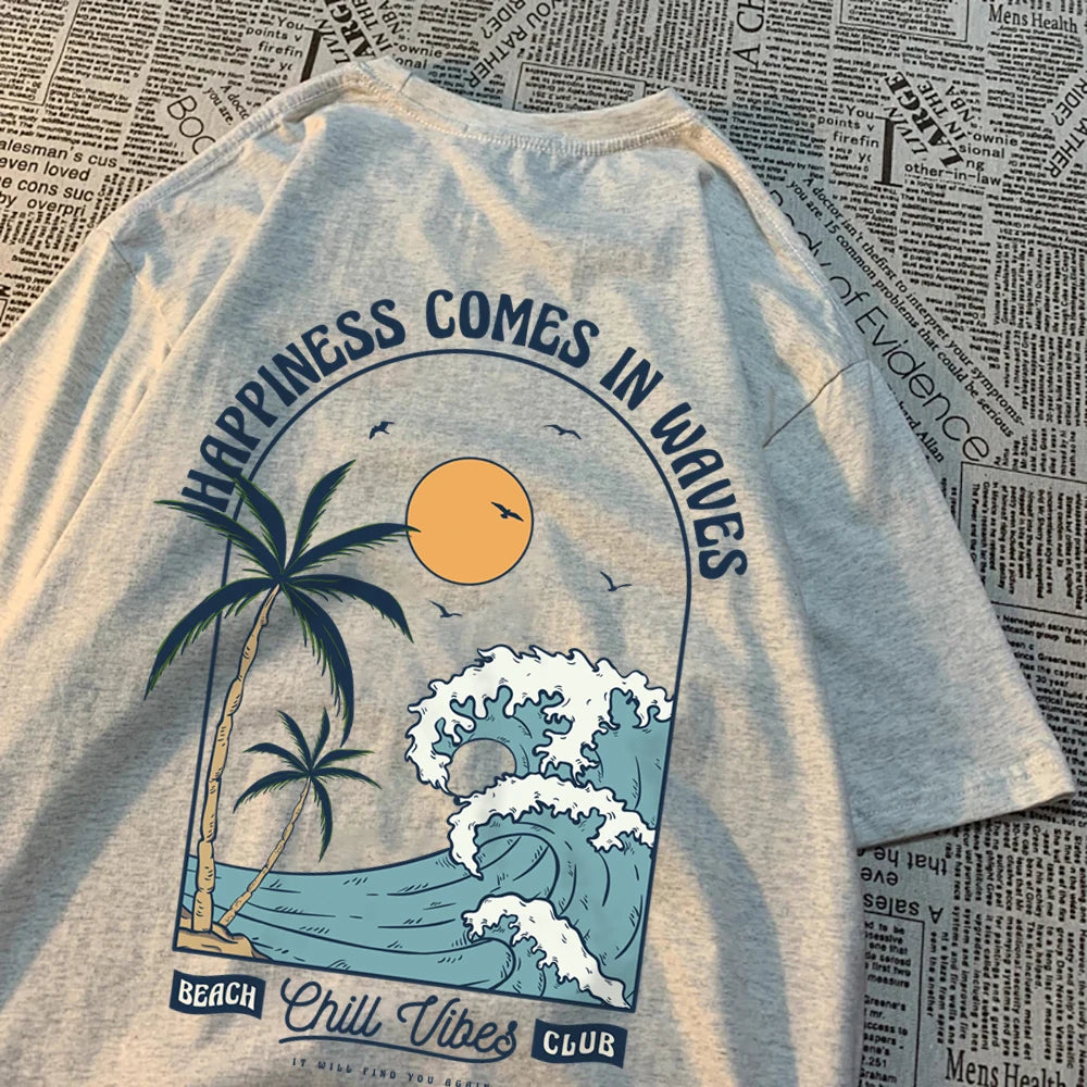 Grey cotton tee with a large back print of a breaking wave, palm trees and a low sun, under the arched words Happiness Comes In Waves