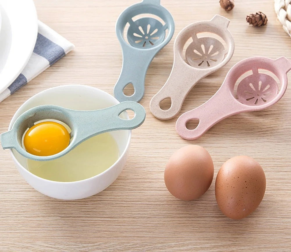 Four egg separators in blue, khaki, green and pink beside a bowl and two eggs